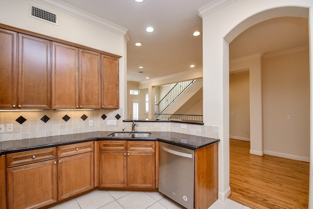 kitchen featuring dark stone countertops, crown molding, dishwasher, and sink