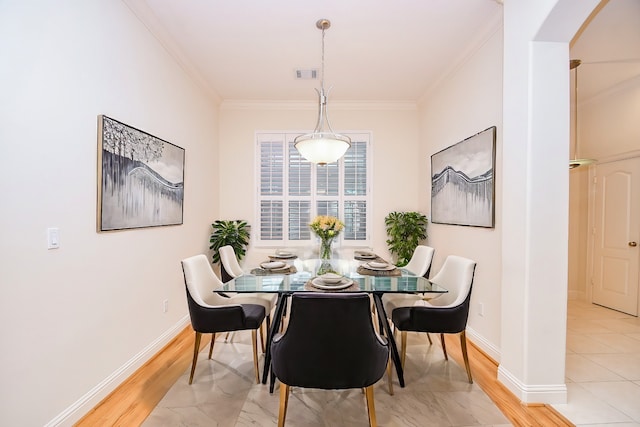 dining space featuring light wood-type flooring and ornamental molding