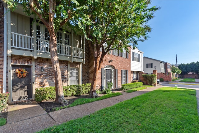 view of property featuring a balcony and a front yard