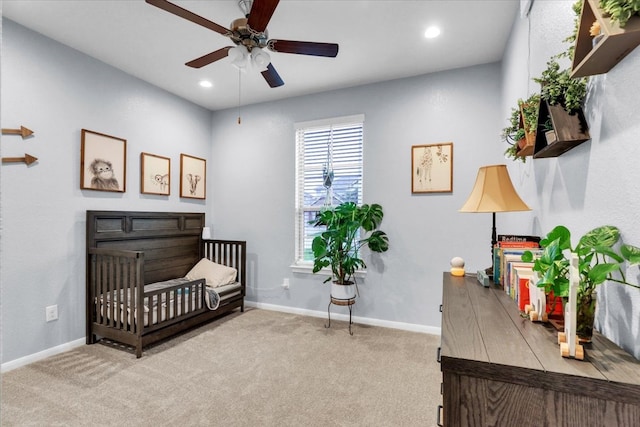 bedroom featuring a crib, light colored carpet, and ceiling fan