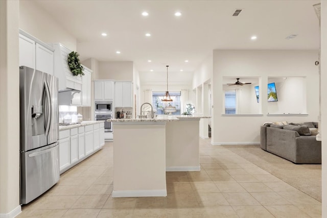 kitchen featuring light stone countertops, stainless steel appliances, a kitchen island with sink, white cabinets, and ceiling fan with notable chandelier