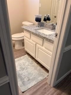 bathroom with vanity, wood-type flooring, and toilet