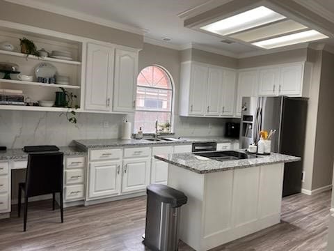 kitchen featuring white cabinetry, a center island, light stone counters, and stainless steel refrigerator with ice dispenser