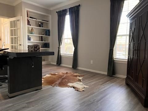 office area featuring built in shelves, wood-type flooring, and ornamental molding