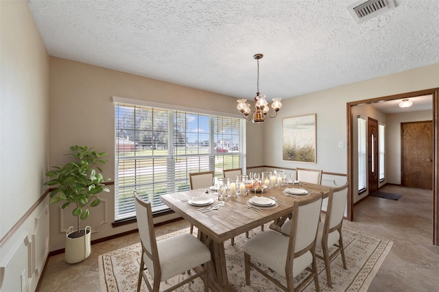 dining area with a textured ceiling and an inviting chandelier