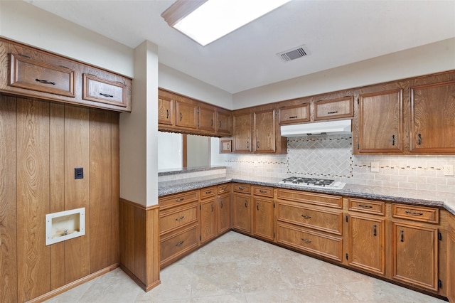 kitchen with backsplash, light stone countertops, and stainless steel gas cooktop