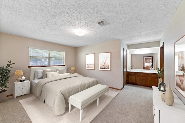 carpeted bedroom with ensuite bathroom and a textured ceiling