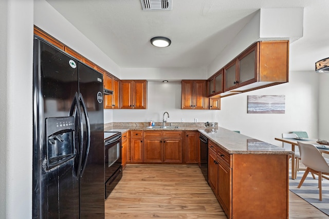 kitchen featuring brown cabinetry, visible vents, a sink, and black appliances