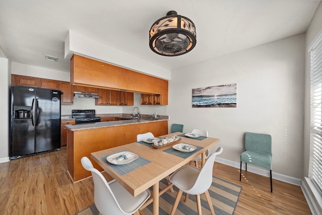 dining space with light wood-style flooring, baseboards, and visible vents