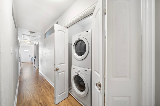 washroom featuring stacked washer and dryer, visible vents, light wood-style flooring, and laundry area