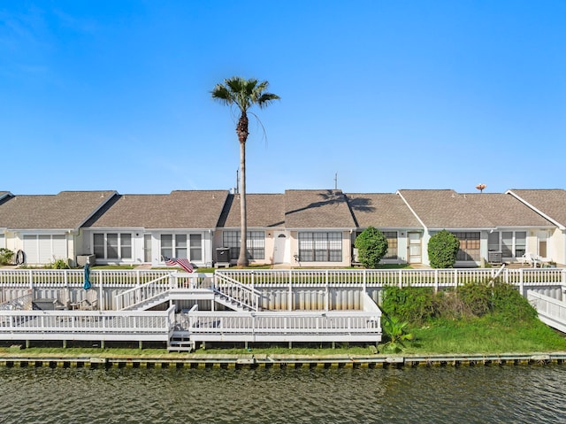 back of property featuring a deck with water view, fence private yard, and roof with shingles