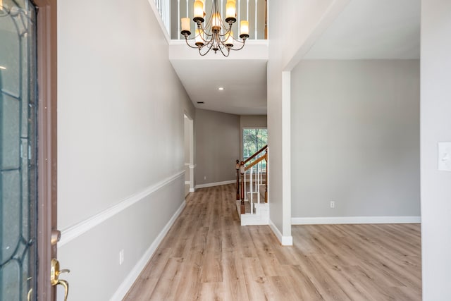 entrance foyer featuring light hardwood / wood-style floors, a towering ceiling, and an inviting chandelier