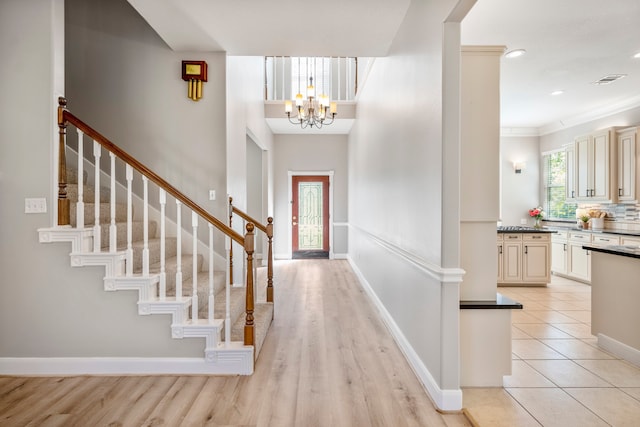 entrance foyer with light hardwood / wood-style flooring, an inviting chandelier, and ornamental molding