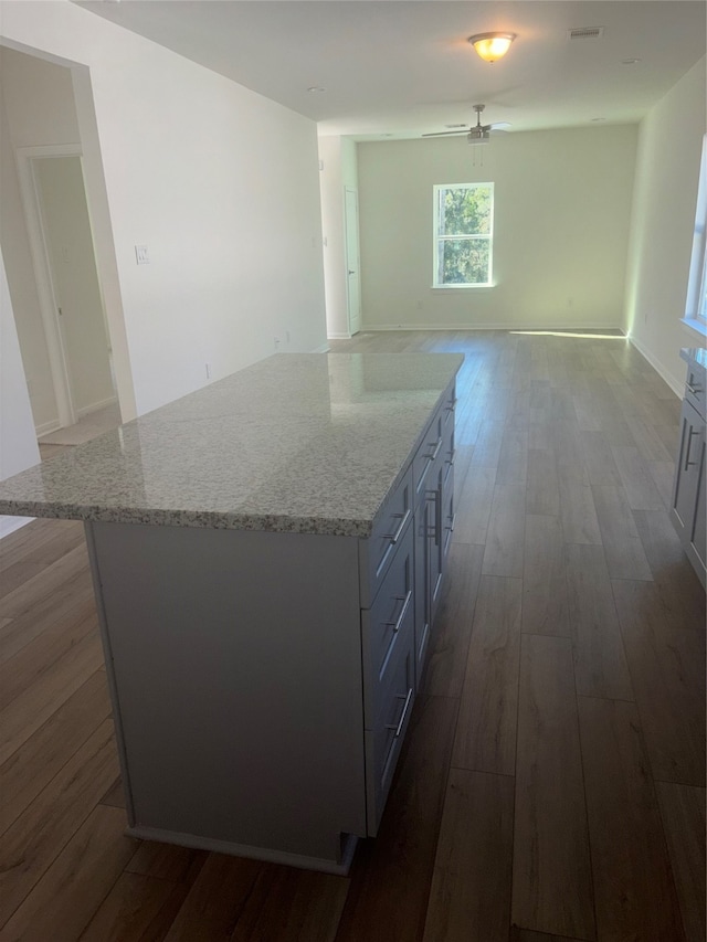 kitchen with light stone countertops, hardwood / wood-style floors, and a center island