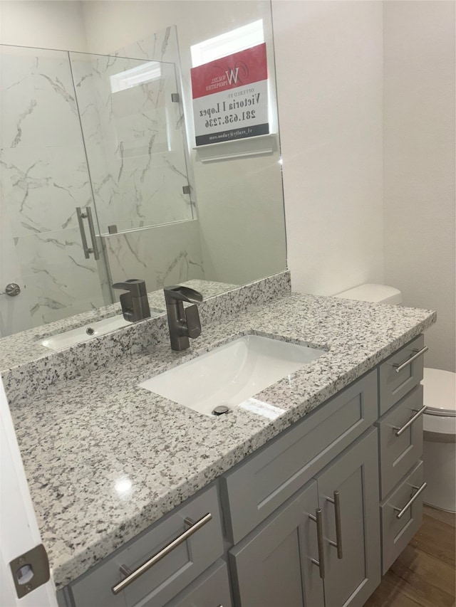 bathroom with vanity, hardwood / wood-style flooring, toilet, and an enclosed shower