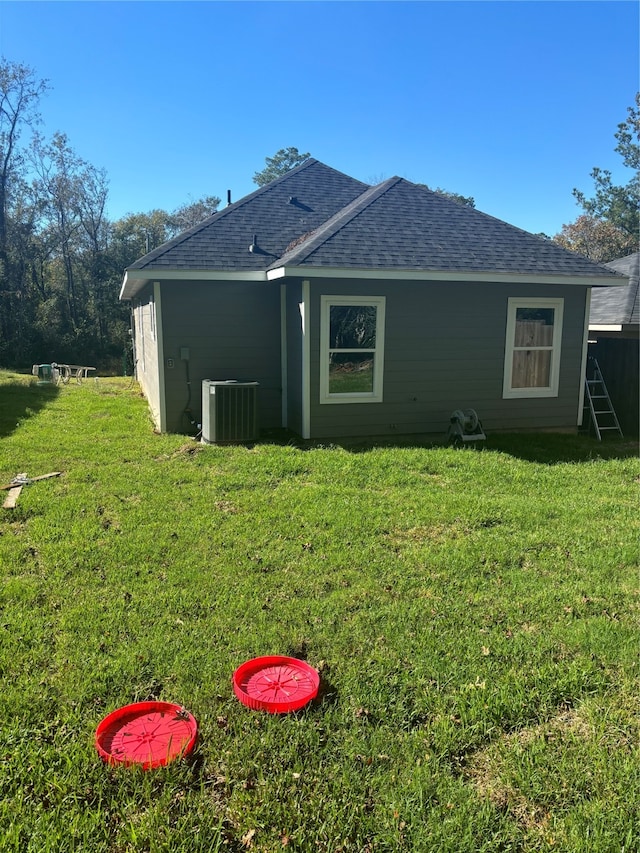 back of house with cooling unit and a yard