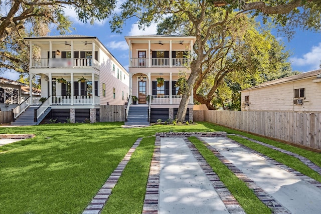 back of house with a porch, a balcony, ceiling fan, and a lawn