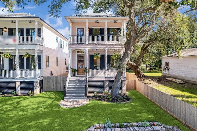 view of front of property featuring covered porch, a front lawn, a balcony, and ceiling fan