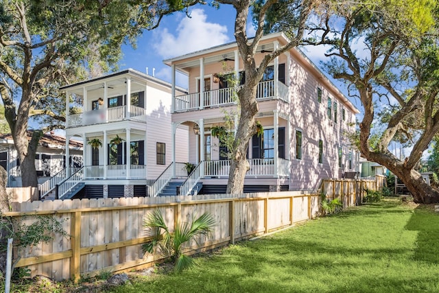 rear view of property featuring covered porch, a yard, a balcony, and ceiling fan