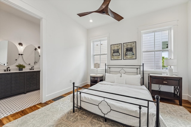 bedroom with multiple windows, wood-type flooring, ceiling fan, and sink