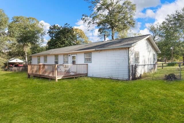 rear view of property featuring a wooden deck and a lawn