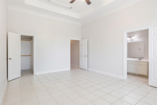 unfurnished bedroom featuring ceiling fan, light tile patterned flooring, a raised ceiling, and ensuite bath