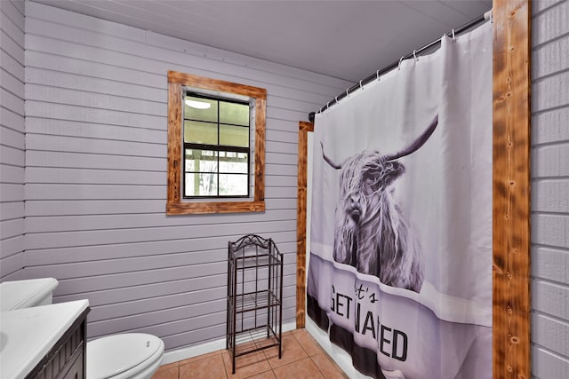 bathroom featuring walk in shower, vanity, wooden walls, tile patterned flooring, and toilet