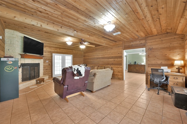 tiled living room with a stone fireplace, ceiling fan, wooden walls, and wood ceiling