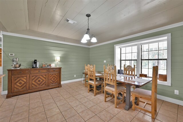 dining space with a notable chandelier, light tile patterned flooring, lofted ceiling, and wooden walls