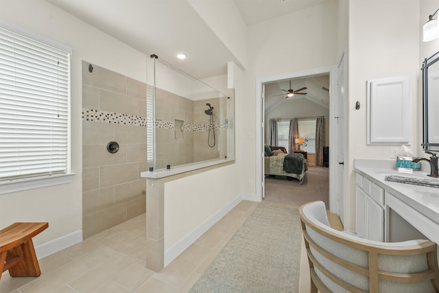 bathroom with vanity, vaulted ceiling, tile patterned flooring, ceiling fan, and a tile shower