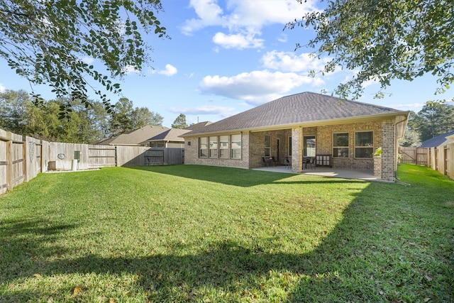 rear view of property with a yard and a patio