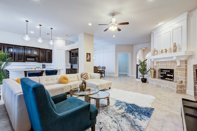 living room featuring a fireplace, light tile patterned floors, and ceiling fan