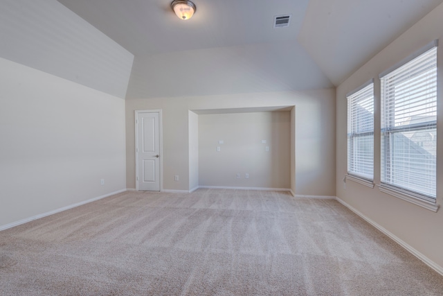 carpeted empty room featuring vaulted ceiling