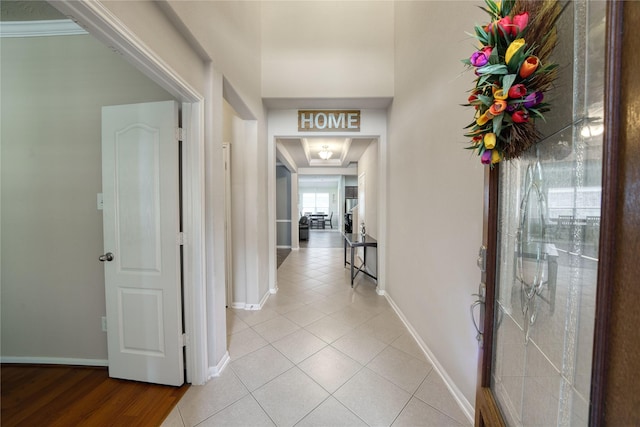 hallway with crown molding and light tile patterned flooring