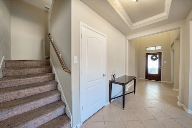 foyer featuring light tile patterned floors, a tray ceiling, and crown molding