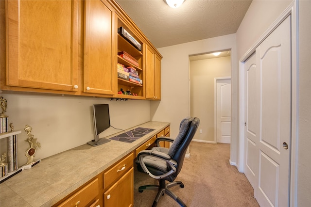 carpeted home office with a textured ceiling and built in desk