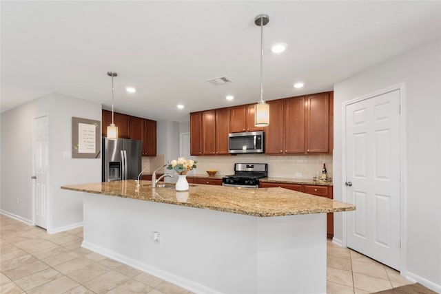 kitchen featuring appliances with stainless steel finishes, decorative light fixtures, a kitchen island with sink, and sink