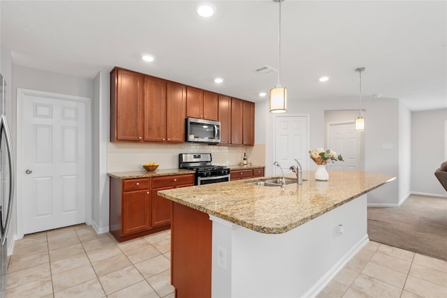 kitchen featuring a center island with sink, sink, light stone countertops, appliances with stainless steel finishes, and decorative light fixtures