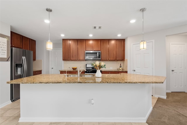 kitchen featuring light stone countertops, a center island with sink, stainless steel appliances, and decorative light fixtures