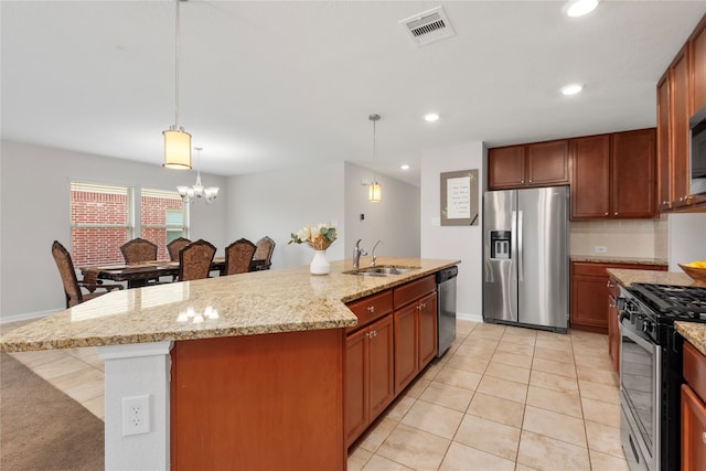 kitchen with a kitchen island with sink, sink, decorative light fixtures, light stone counters, and stainless steel appliances