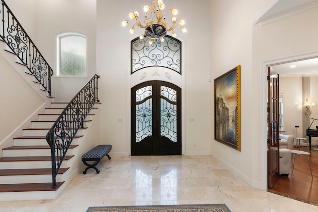 entryway featuring french doors, a high ceiling, a notable chandelier, crown molding, and light hardwood / wood-style floors