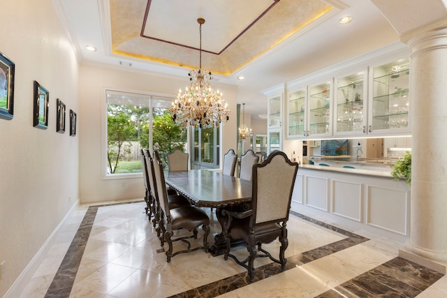 dining area featuring a raised ceiling, crown molding, decorative columns, and a notable chandelier