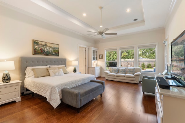 bedroom with a tray ceiling, ceiling fan, crown molding, and dark wood-type flooring