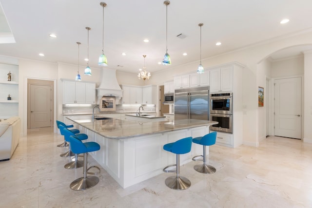 kitchen with built in appliances, a breakfast bar, pendant lighting, and premium range hood