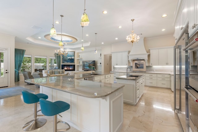 kitchen featuring white cabinetry, a fireplace, a spacious island, and decorative light fixtures