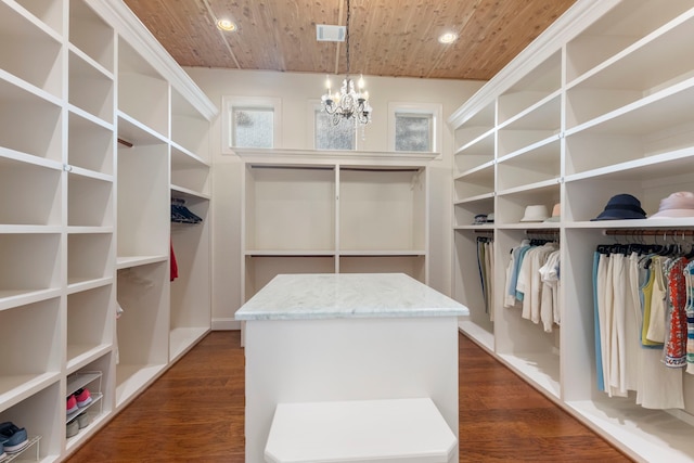 spacious closet with dark hardwood / wood-style floors and a notable chandelier