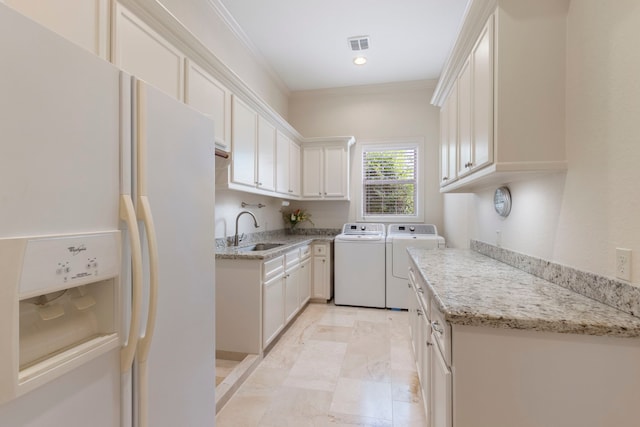 laundry area featuring washing machine and clothes dryer, cabinets, crown molding, and sink