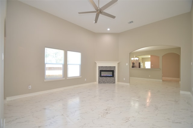 unfurnished living room with ceiling fan with notable chandelier and high vaulted ceiling