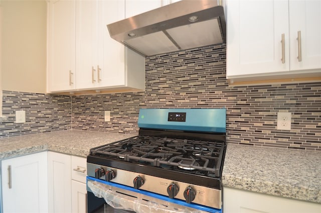 kitchen with decorative backsplash, white cabinetry, stainless steel range with gas cooktop, and range hood