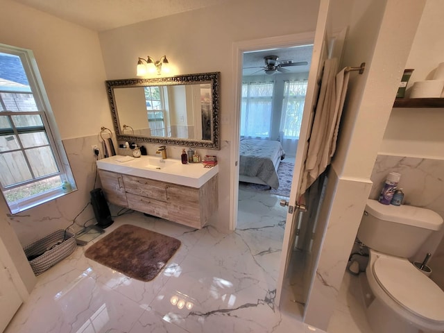 bathroom with vanity, toilet, tile walls, and ceiling fan